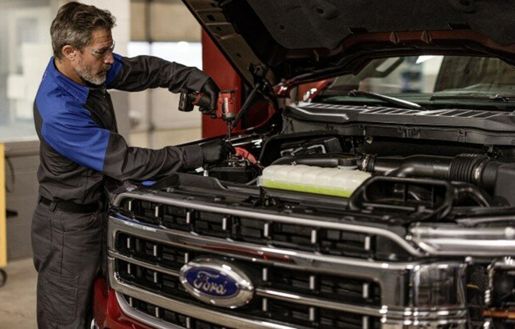 Truck mechanic inspecting engine under raised hood during commercial vehicle maintenance